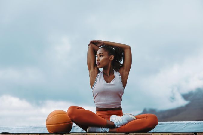 Athlete woman stretching arms outdoors on building terrace