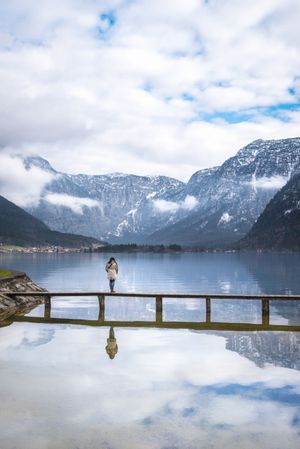 Peaceful woman enjoying an alpine scenery on a bridge over alpine lake