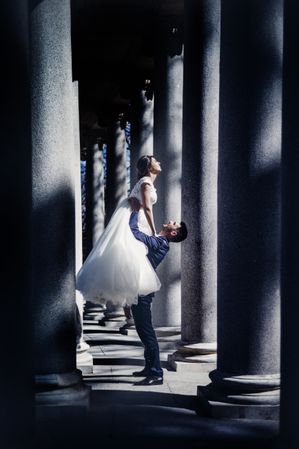 Newly weds having fun between columns