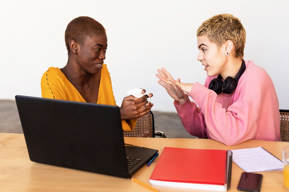 Lesbian couple talking over laptop on breakfast table