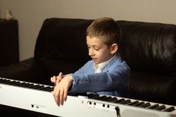 Young boy in blue blazer adjusting the piano