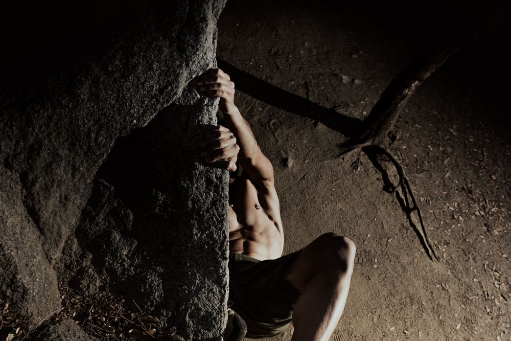 Man practicing rock climbing among large rocks in a forest