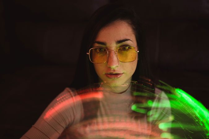 Young woman with fairy lights in darkness