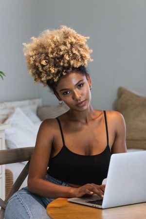 Black woman with laptop sitting on chair during breakfast