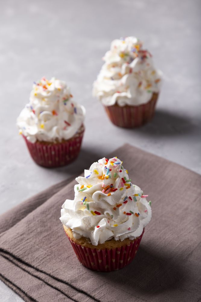 Tasty party cupcakes on the table. Cupcakes with whipped cream.