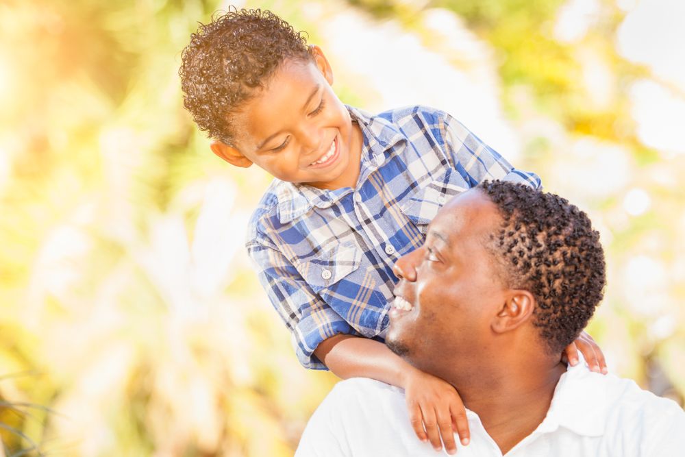 Young Black Son Talking At Father Outdoors