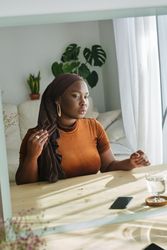 Beautiful Black woman in hijab looking in mirror