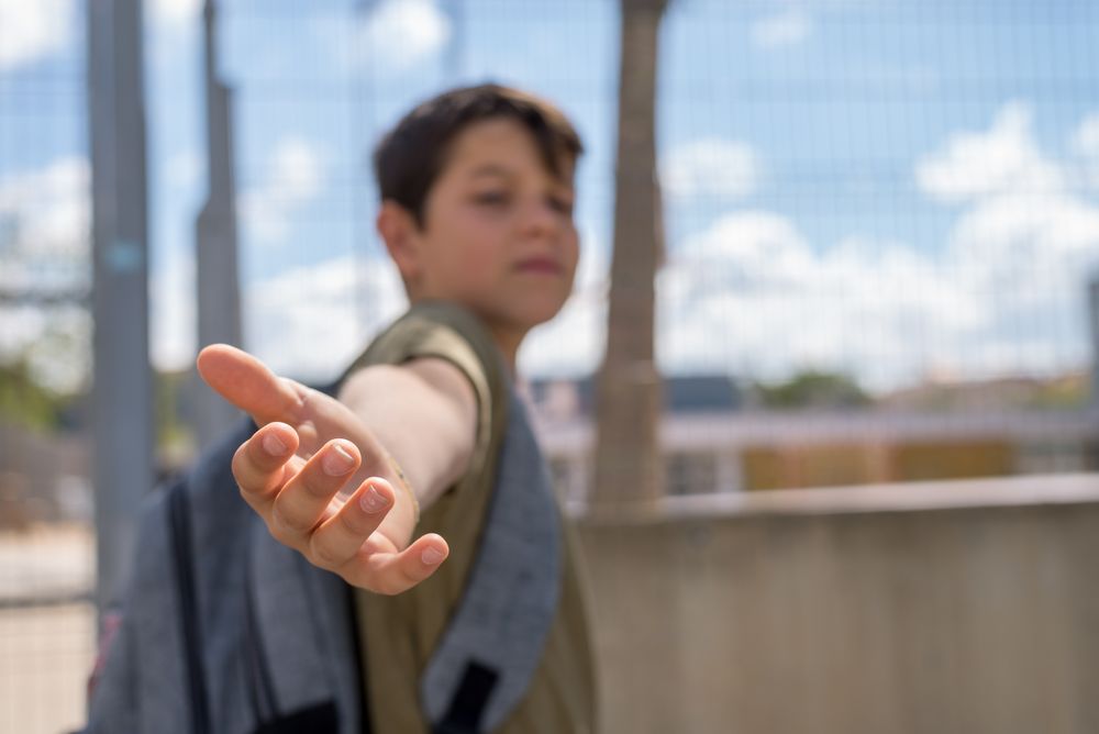 Teenager out of focused standing outside school gate reaching back