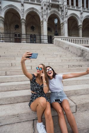 Laughing women taking selfie on stairs at old building
