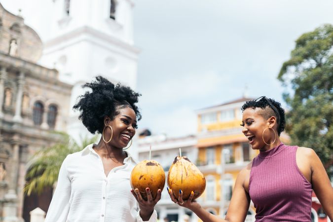 Latin American women having fun in the city drinking coconuts