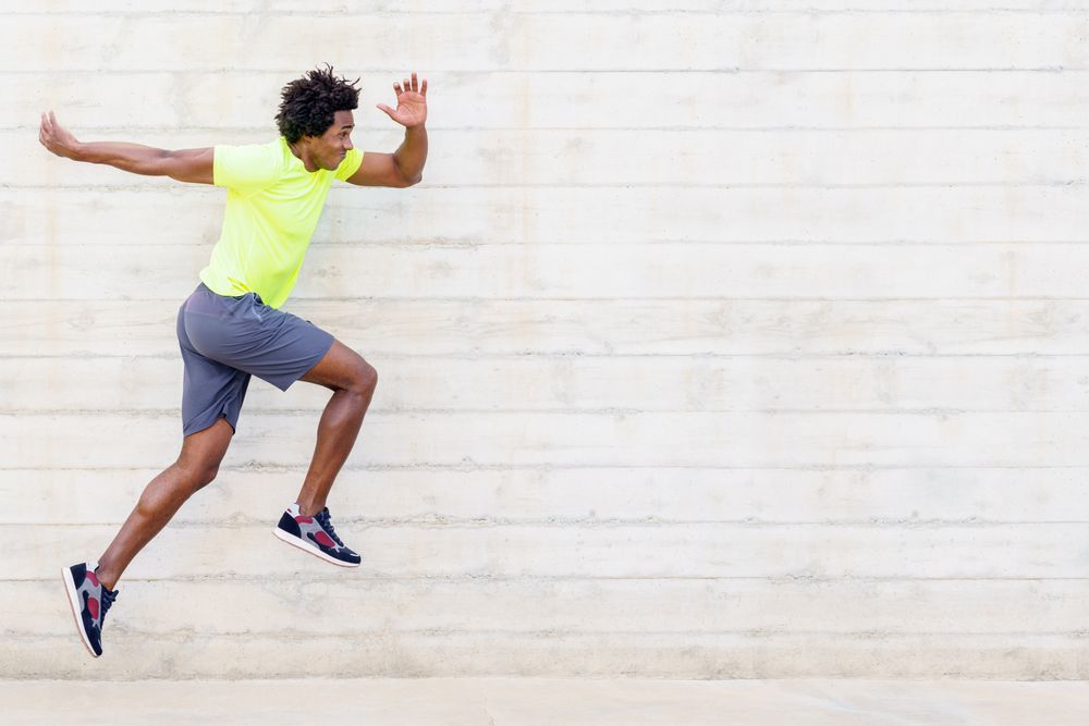 Side view of man doing running jumps in neon shirt