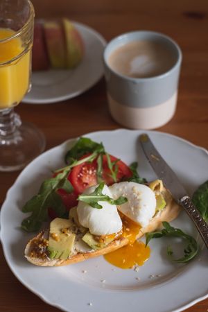 Bruschetta with poached egg on toast beside orange juice and coffee