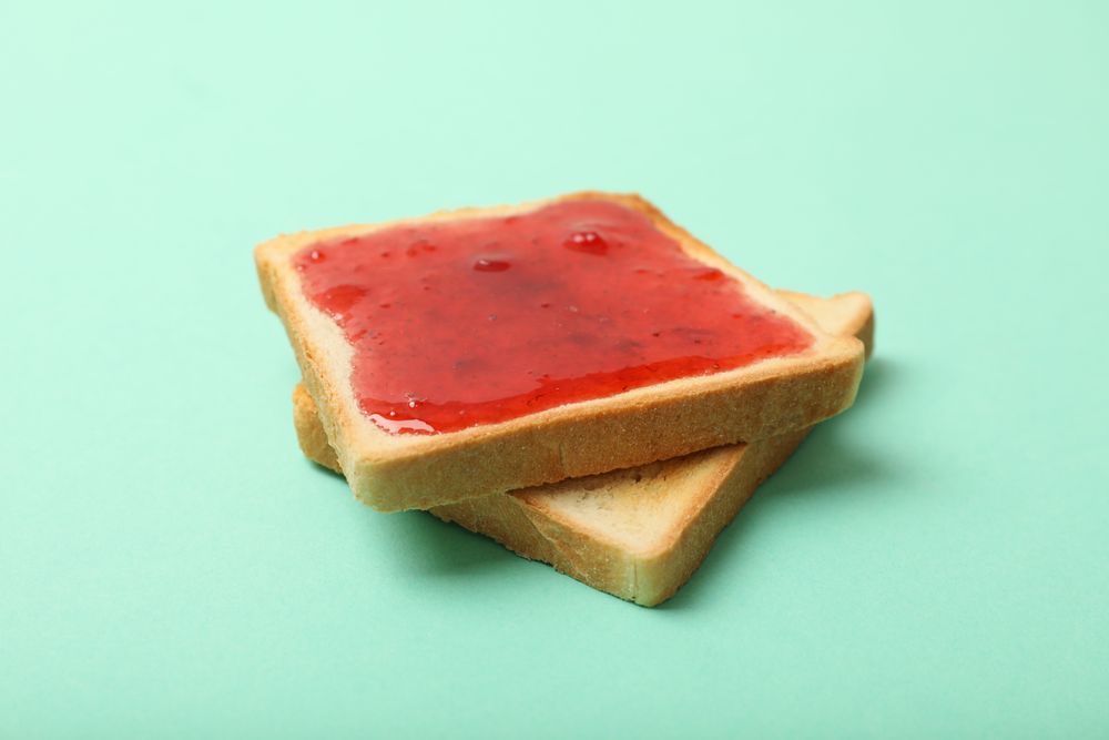 Toasts with strawberry jam on mint background, close up