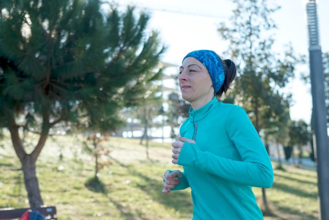 Woman in blue running outdoors on sunny fall day