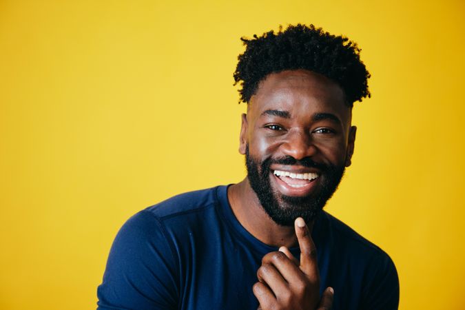 Portrait of joking Black man pointing finger on yellow background