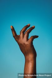 Cropped image of Black hand against blue background 0LX1E0