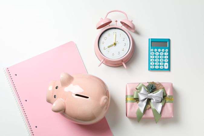 Piggy bank, watch, calculator and gift box on blank background, top view