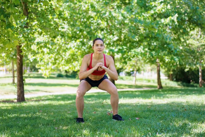 Fit woman squatting in park