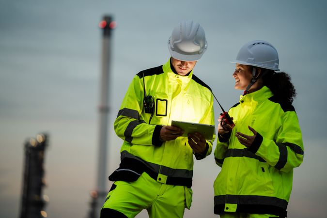 Engineer worker watching work monitor on digital tablet at refinery factory at night