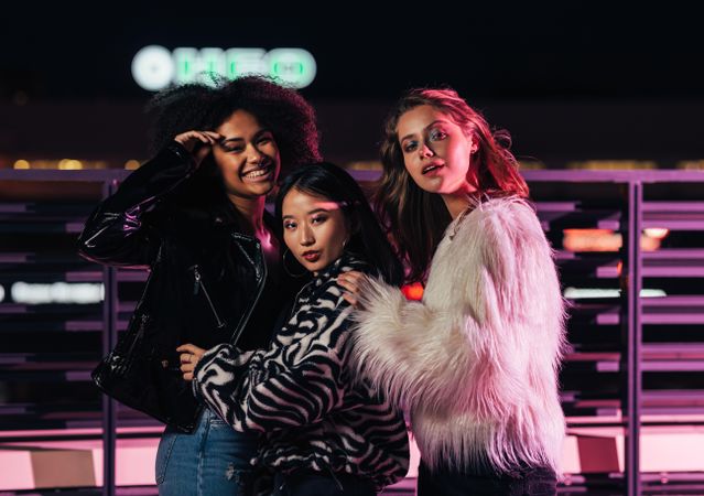 Multi-ethnic group of trendy women on terrace at night