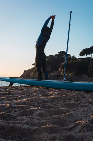 Man practicing paddle surfing with neoprene in a sunrise