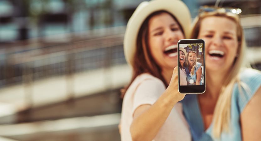 Women smiling and taking selfie on sunny day, copy space