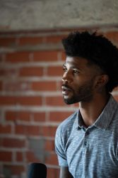 Close up of man in front of an exposed brick wall