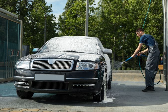 A man washes a car in a manual car wash. Clear car