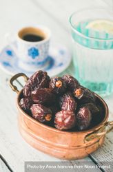 Copper bowl of dates with espresso and water in background 5QKJmb