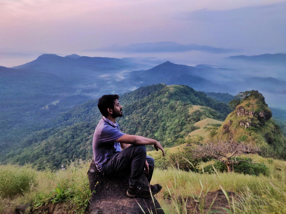 Man sitting on rock looking at mountainous landscape