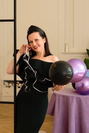 Woman with balloons, smiling at birthday party.