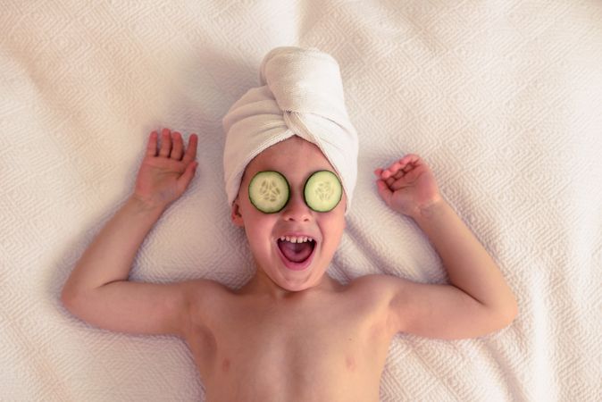 Cheerful boy with cucumber on eyes
