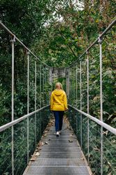 Cheerful female tourist standing on hanging bridge in summer