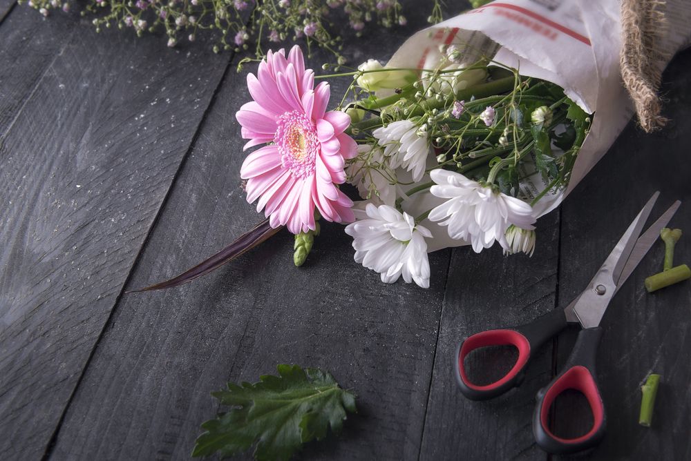 Wrapped flower bouquet and scissors on wooden table