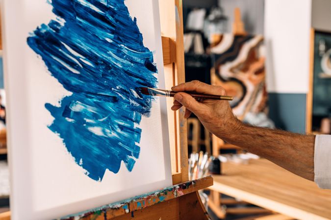 Male hand painting with blue paint