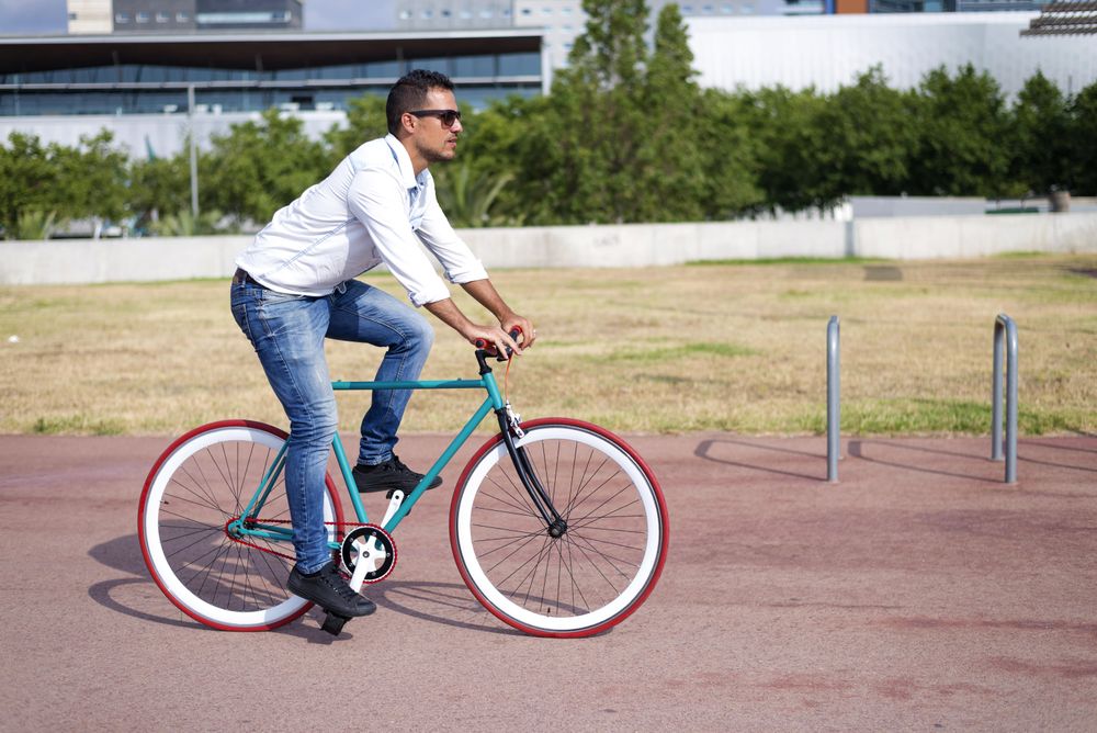 Male riding red and green bike outside on sunny day