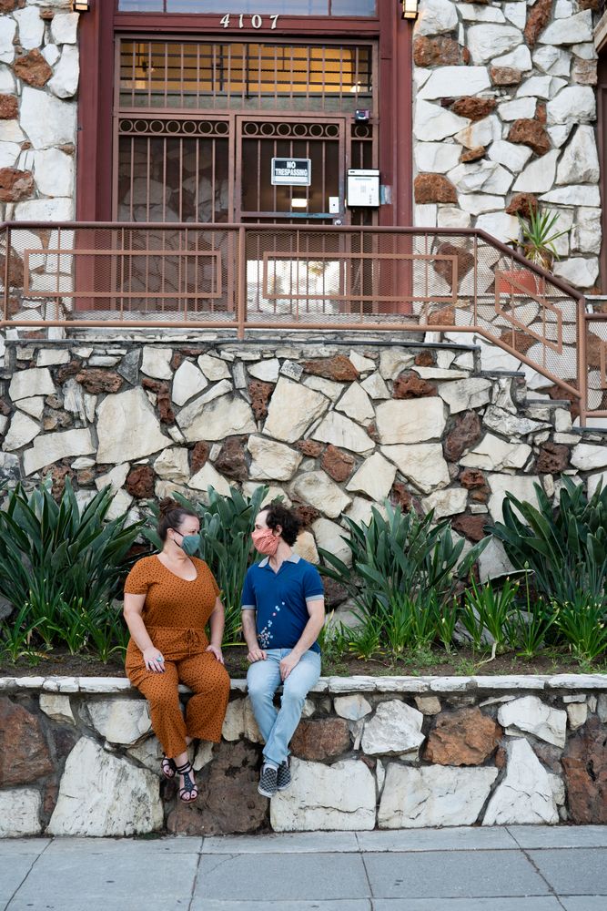 Happy friends talking outside wearing masks in front of apartment building