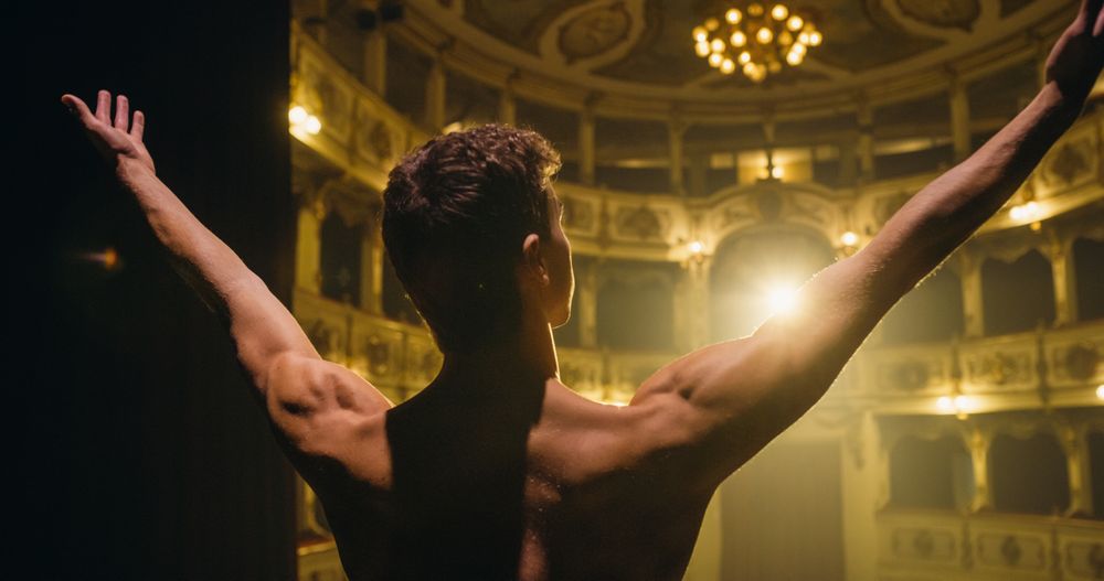 Cinematic Back View of Young Classical Ballet Male Dancer Walking Out to Classic Theatre Stage with Spotlights for the Curtain Call.
