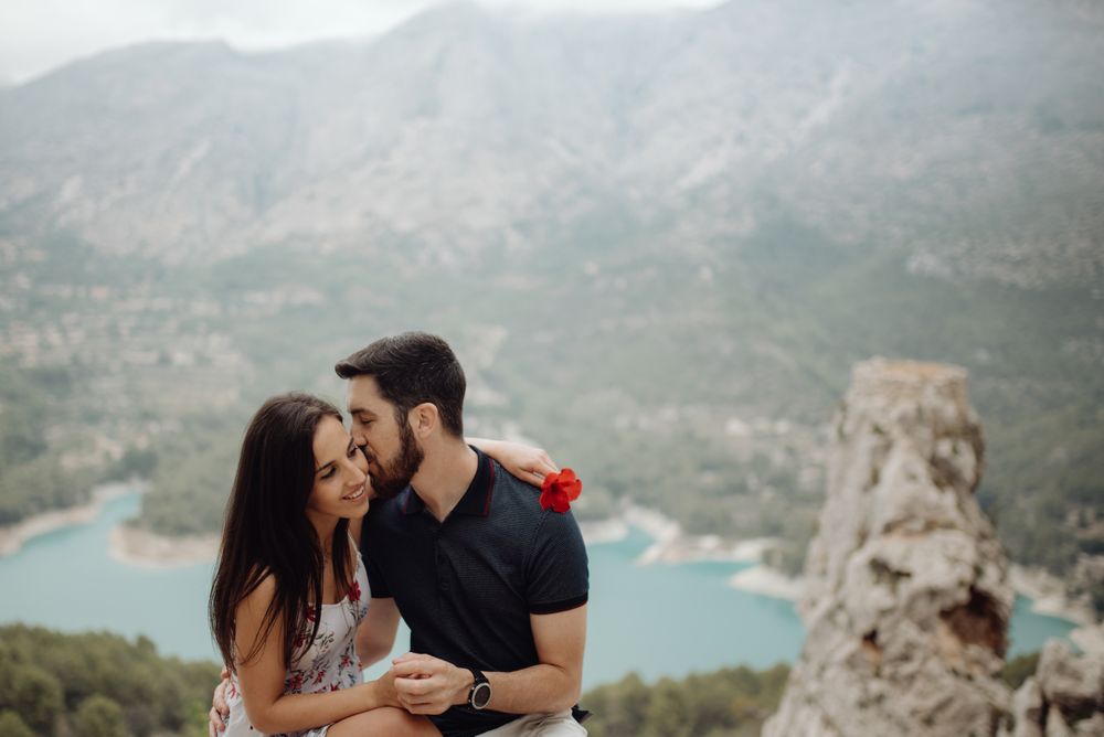 Affectionate casual couple embracing and resting on mountain top