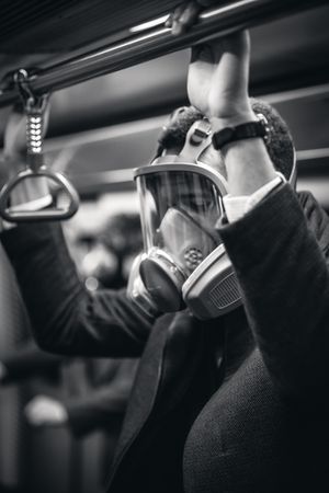 Grayscale photo of person wearing gas mask and suit in train