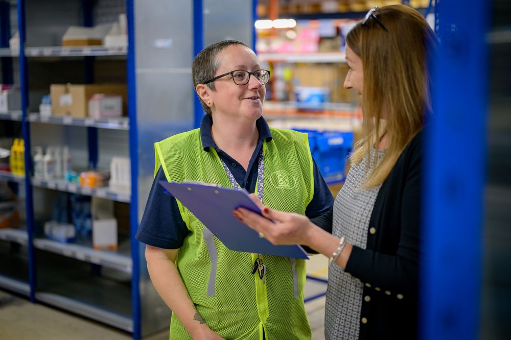 Two women talking with clipboard in warehouse