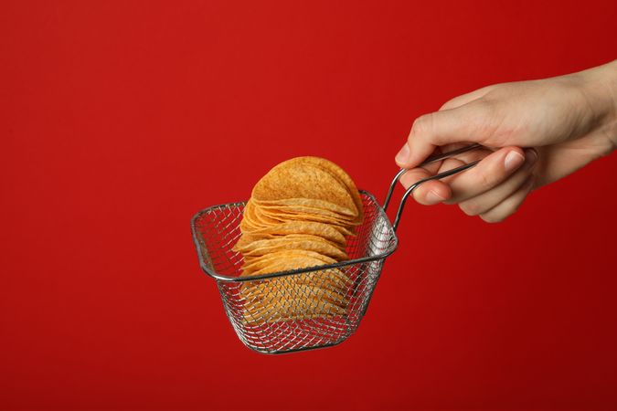 Deep-fried potato chips on a red background