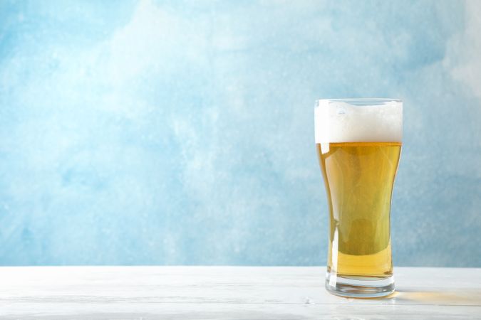 Mug with beer on wooden table, space for text