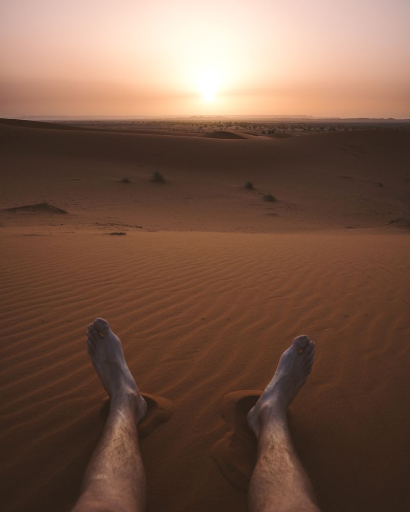 Crop legs of traveler on sandy dune