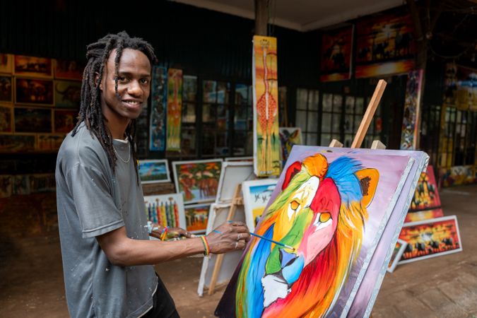 Black man smiling at camera in paint studio