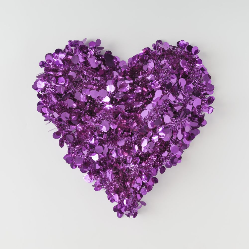Purple confetti shaped in heart on light background