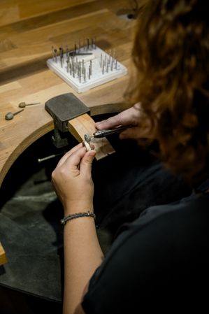 unrecognizable woman grinding ring in jewelry atelier