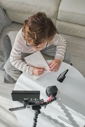 Boy writing and looking at camera