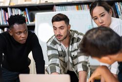 Serious colleagues leaning over desk urgently working on project