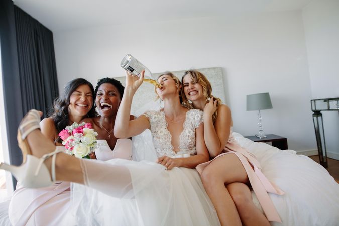 Bride and bridesmaids having fun in a hotel room before wedding